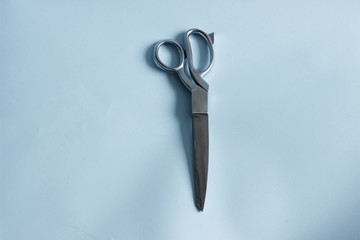 Silver scissors with pink white violet sewing threads on blue pastel background