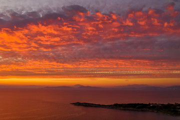 Fototapeta na wymiar Luftaufnahme eines romantischen Sonnenunterganges über dem Meer mit roten und orangenen Farbtönen
