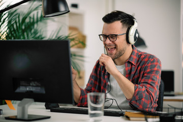 Attractive businessman in office. Young programmer with headphones singing at work.	