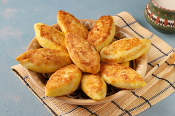 Cottage cheese pancakes, homemade traditional Ukrainian dish syrniki with semolina and cup of milk on a plate on a light blue background