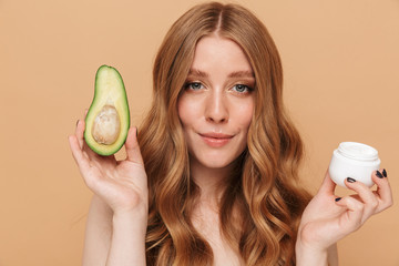 Portrait of young half-naked woman holding avocado and face cream jar