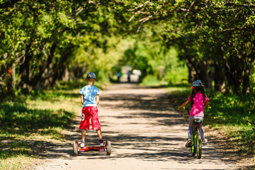 Girl on a bicycle and a boy on a gyroscope are riding together