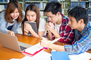 Multiethnic college students checking test results, looking at laptop screen at library.