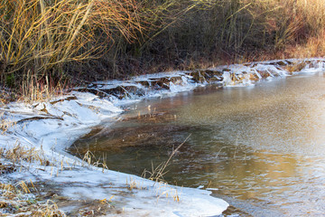 Lakeshore of a frozen lake and ice floes hanging down