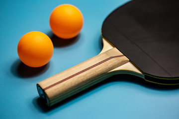Close up of ping-pong racket and two orange balls on the blue background, sport concept