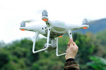 Hand landing a flying drone in the spring countryside