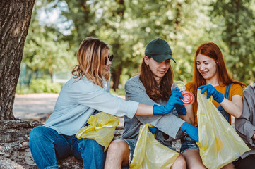 Group of activists friends collecting plastic waste at the park. Environmental conservation.