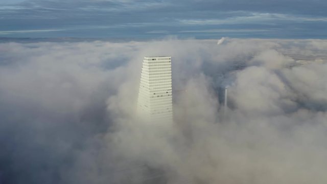 Waves of sea of fog over the Basel city around Roche tower at sunrise with rainbow halo. Fly around shot from a drone.