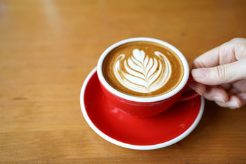 Hot Mocha - Holding a cup of coffee with milk, cocoa and beautiful latte art on wooden  table and copy space, Perfect for breakfast time.