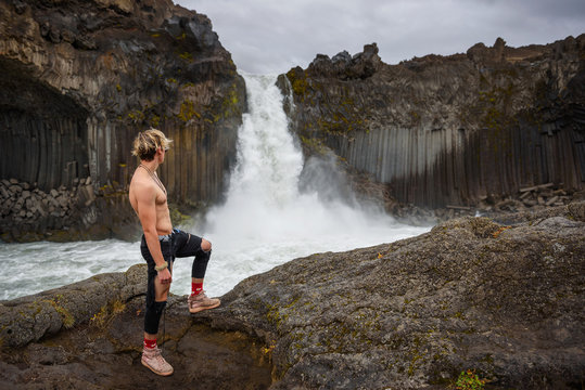 Shirtless and muscular boy looks at the Aldeyjarfoss waterfall in Iceland - Powered by Adobe