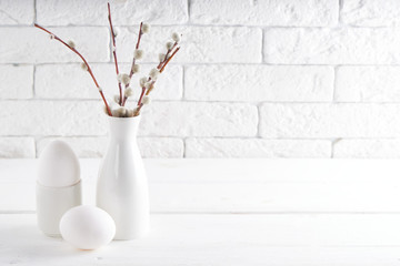 White vase with willow branch , white egg and cups on a white table Copy space Easter concept