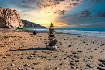 Fototapeta premium Meditative Stone Stack on a Mediterranean Beach in Southern Italy at Sunset