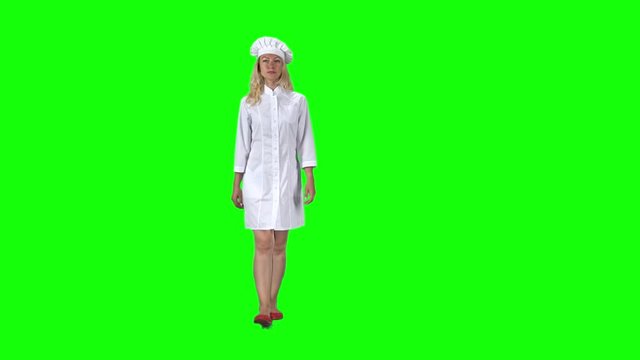 Blonde cook chef in white uniform and hat going against a green screen. Slow motion