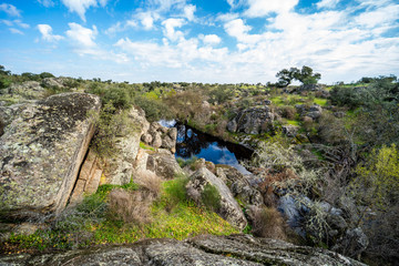 Pisaje rocoso con un lago y cielo con nubes