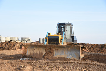 Obraz premium Bulldozer during of large construction jobs at building site. Crawler tractor dozer for earth-moving. Land clearing, grading, pool excavation, utility trenching and foundation digging.