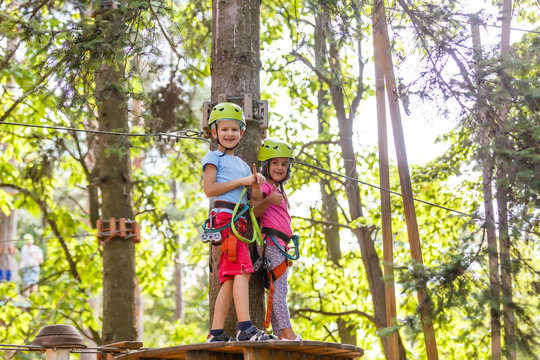 Adventure Climbing High Wire Park - Children On Course Rope Park In Mountain Helmet And Safety Equipment