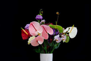 Colorful flower bouquet with Flamingo Flowers, Lisianthus or Eustoma, Orchid and rolled up fern isolated on black background