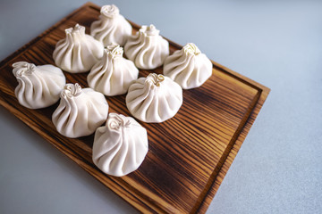 Khinkali dumplings pastry dish on a wooden board, isolated on gray background