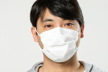 感染症予防の為に衛生マスクをしている日本人男性の顔アップ正面