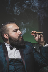 Man with a beard and a green suit, smoking cigars and smoking in profile.