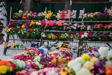 a point of sale with many artificial flowers, bouquets and wreaths near the cemetery sells jewelry and traditional offerings to the graves of the dead in memory of living relatives