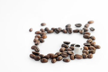 Miniature cup of coffee surrounded by coffee beans