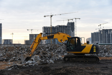 Yellow excavator at a construction site during crushing stones after the demolition of an old building. Salvaging and recycling construction waste. Reuse concrete