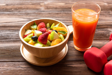 Healthy lifestyle for woman diet with fresh orange juice fruits salad and dumbbells sport equipment fruit healthy green apples on wooden background.  Healthy Concept..