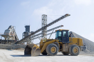 Wheel medium-sized Loader and belt conveyors and piles of rubble in Gravel Quarry