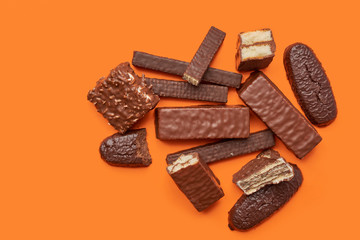 Chocolate waffle wafer desserts and bars on vibrant orange background top view. Copy space poster