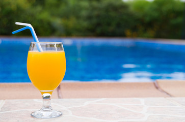 Orange juice near the pool. Space for text.