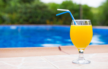 Orange juice near the pool. Space for text.