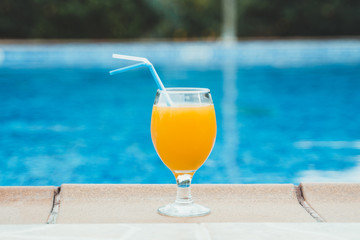 Orange juice near the pool. Space for text.
