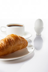 Breakfast. Croissant, coffee and soft-boiled egg. High key. Selective focus.