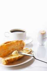 Breakfast. Croissant with butter, coffee and soft-boiled egg. High key. Selective focus.