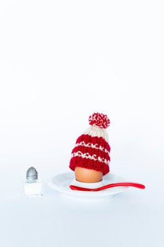 Fun breakfast concept with a boiled egg wearing a knitted woolen hat on white background.