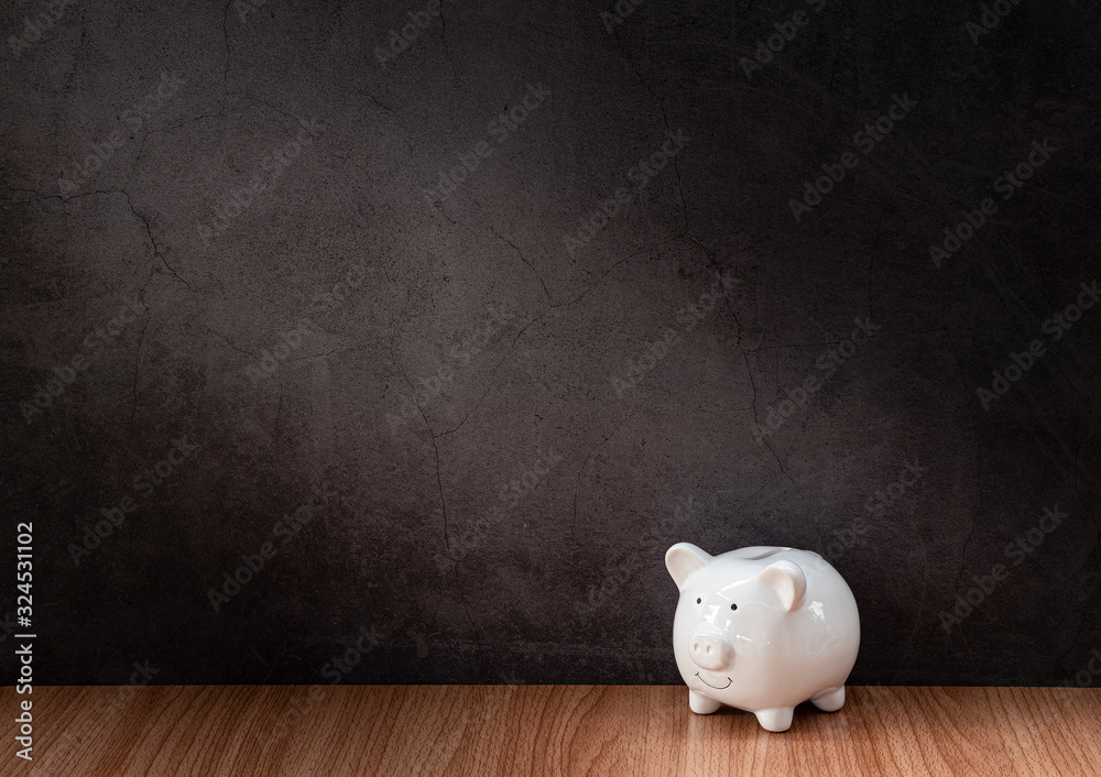 Wall mural white piggy bank on a wooden table with old gray concrete walls.