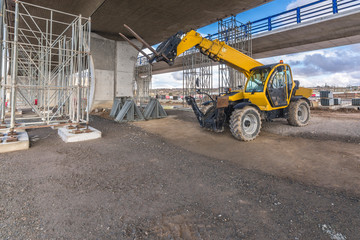 Telehandler on a construction site, preparing to raise construction parts