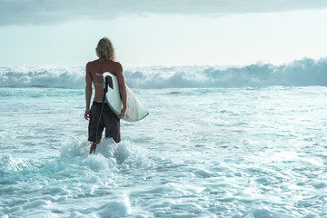 Male surfer with a short Board goes into the ocean with big waves, a challenge to nature concept