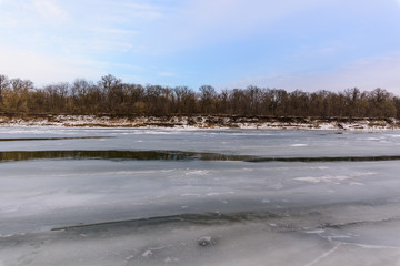 panorama of the winter landscape on the river covered with ice at sunset. pink sky. photo for banner