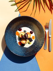exquisite restaurant dish on a flat plate on a colored background. Restaurant serving. View from above