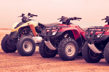Side view of modern multi-colored all-terrain vehicles stand in the desert on a cloudy day