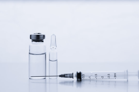 Ampoules for injection. Glass medical vials for vaccination. Transparent bottles and disposable syringe on a white background