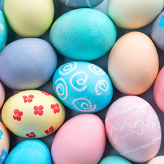 Colorful Easter eggs dyed by colored water with beautiful pattern on a pale blue background, design concept of holiday activity, top view, full frame.