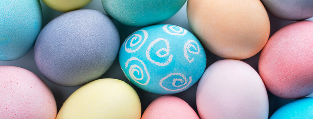 Colorful Easter eggs dyed by colored water with beautiful pattern on a pale blue background, design concept of holiday activity, top view, full frame.