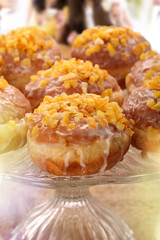 Fresh donuts on a plate and young girls are drinking coffee in the background