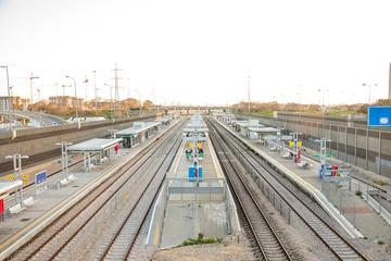 Railroad tracks in the city during daylight hours. There are no trains. People are waiting on the platforms. City Style. Horizontal view.