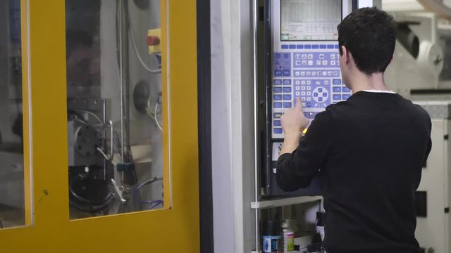 Production Worker Operates the Automatic Injection Molding Machine to Start Production of Molding Housing for the Headlamps in Automotive Factory