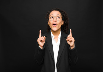 young black woman feeling awed and open mouthed pointing upwards with a shocked and surprised look...