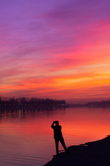 Obraz premium Silhouette of a man taking a photo of a beautiful sunset sky; With copy space